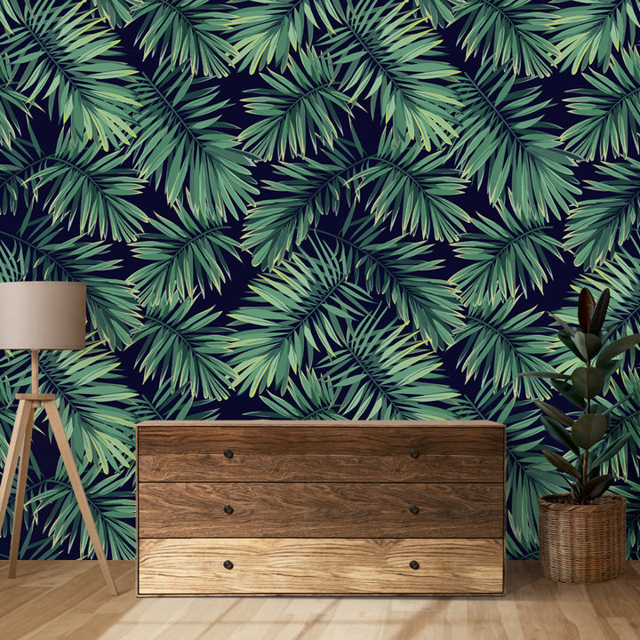 Modern tropical wallpaper with large overlapping palm leaves in rich green tones on dark blue, removable and eco-friendly, ideal for accent walls or home offices.
