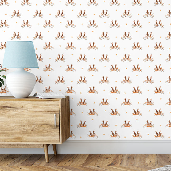 Charming wallpaper featuring monkeys pedaling tandem bicycles among orange stars, creating a cheerful and imaginative nursery or playroom wall design.