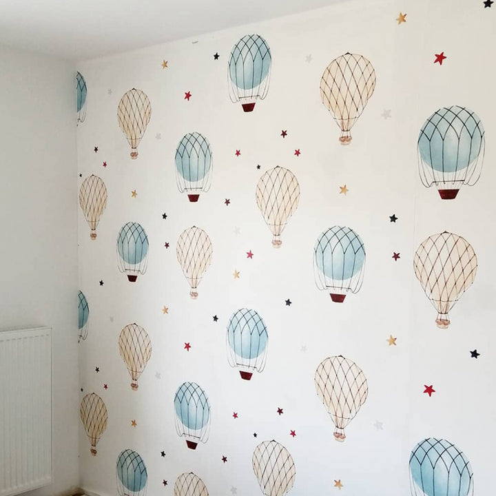 Gender neutral nursery wallpaper featuring soft pastel hot air balloons drifting in a repeating pattern, printed on removable peel and stick or pre-pasted wallpaper.