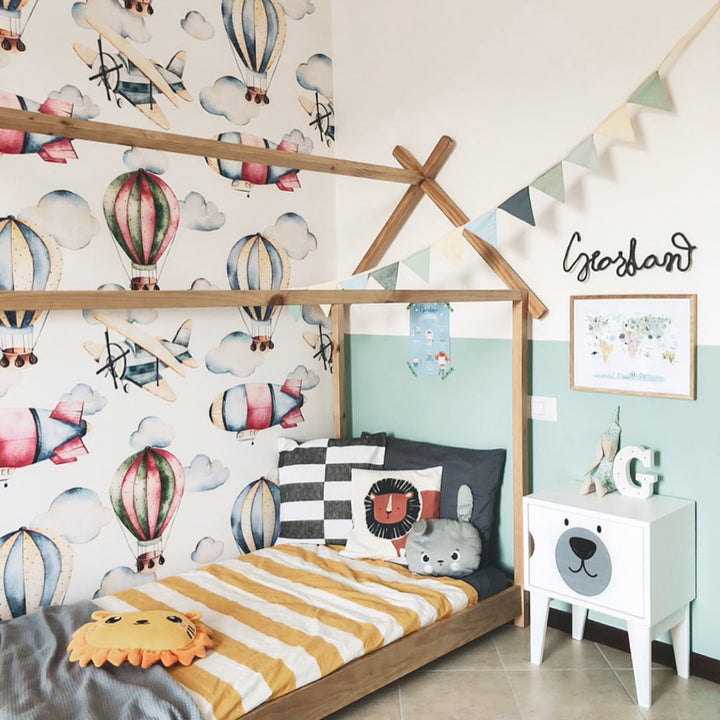 Kids’ balloon and airplane wallpaper with whimsical watercolor aircraft floating among clouds in a repeating pattern, printed on removable, damage-free wallpaper.