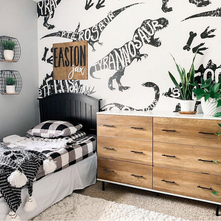 Kids dinosaur mural wallpaper in black and white with giant T-Rex, Stegosaurus, Apatosaurus and more, designed in a graphic typography style for playrooms or bedrooms.