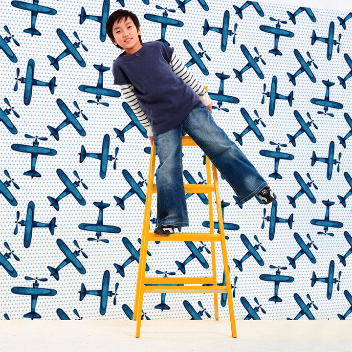 Blue aircraft wallpaper design with scattered watercolor planes on a dotted backdrop, removable and renter friendly, available in peel and stick or pre-pasted formats.