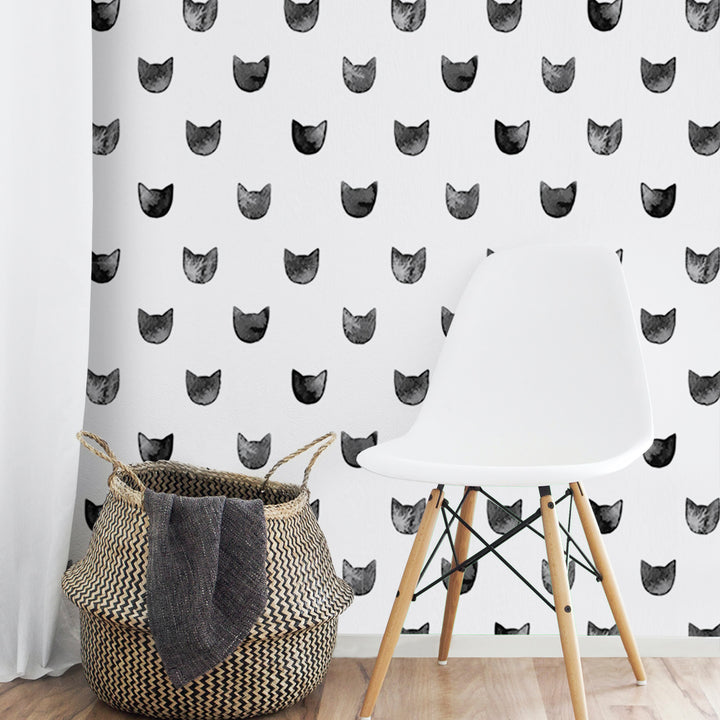 Minimalist cat head wallpaper design with repeating illustrated kitten faces in black and grey, available in damage-free peel and stick or pre-pasted material.