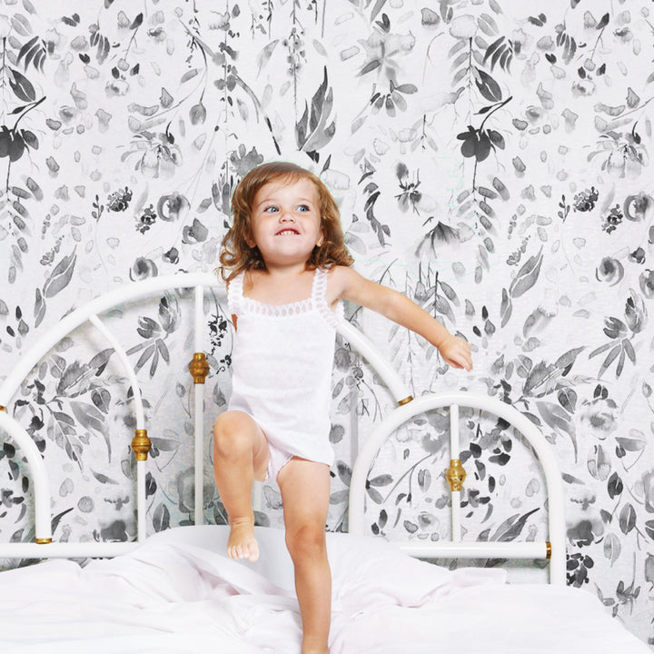 Soft grey floral wallpaper with hand-painted wildflowers, leaves, and cascading vines in a watercolor style, offered in removable peel and stick or pre-pasted material.