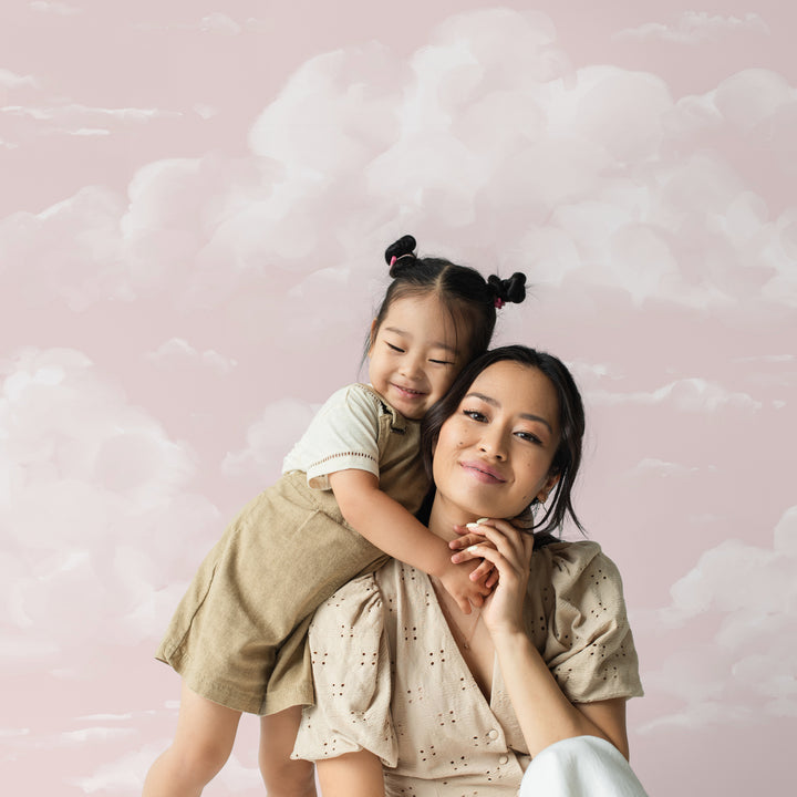 Pink sky cloud mural design with hand-painted clouds across a warm blush tone, available as peel and stick or removable pre-pasted wallpaper.
