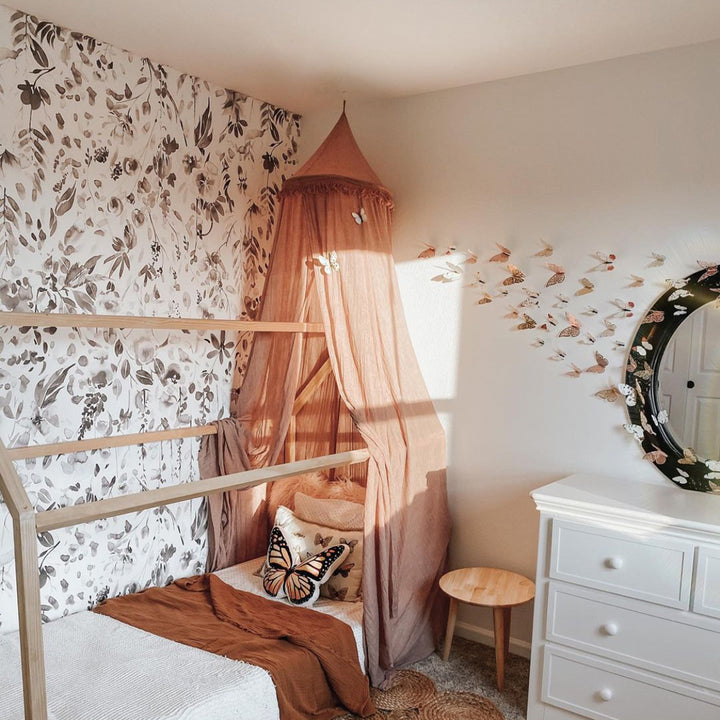 Large-scale grayscale floral wallpaper featuring soft wildflowers, garden stems, and leafy watercolor elements, printed in peel-and-stick or pre-pasted formats.