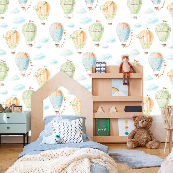 Pastel balloon wallpaper for nursery décor with soft watercolor clouds and vintage style hot air balloons in repeating pattern on white backdrop.