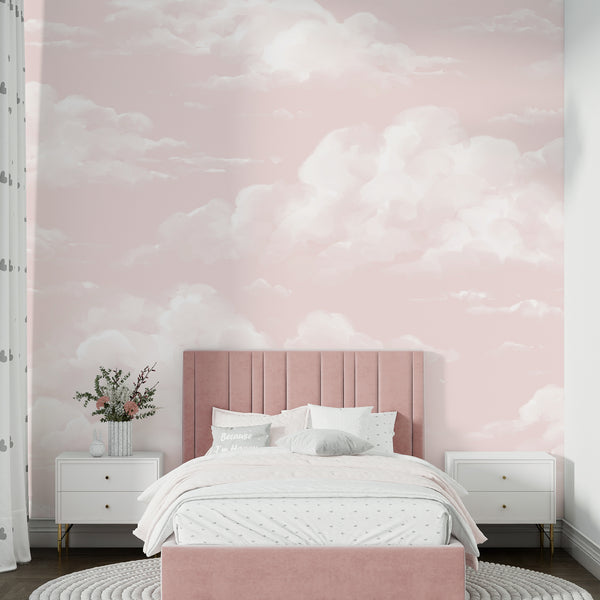 Soft pink cloud wallpaper featuring hand-painted white clouds drifting across a blush sky, available in removable peel and stick or pre-pasted material for nurseries and kids rooms.