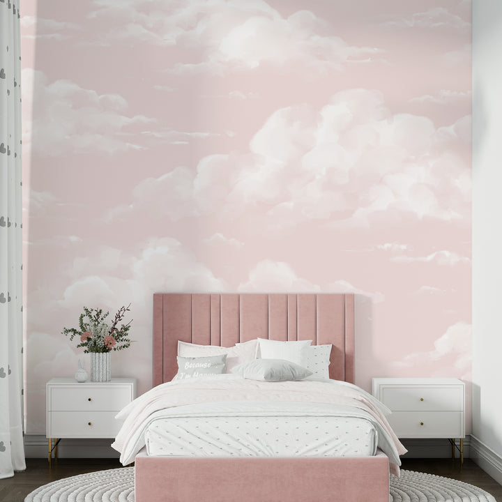 Soft pink cloud wallpaper featuring hand-painted white clouds drifting across a blush sky, available in removable peel and stick or pre-pasted material for nurseries and kids rooms.